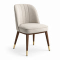 Silla de comedor tapizada beige con patas de madera y detalles de latón